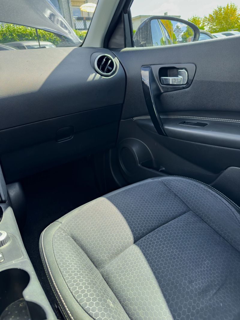 The interior of a modern car, emphasizing the driver's seat and dashboard, with sunlight streaming through the window on a clear day.