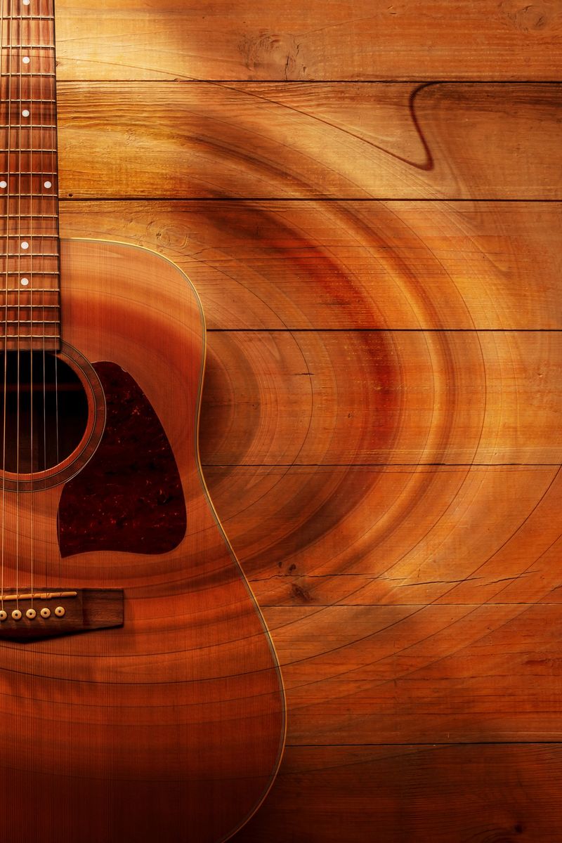 An acoustic guitar rests on a wooden surface. Light enhances the wood's grain, and sound waves ripple gently around. The scene invites creativity and musical moments. Space for copy.
