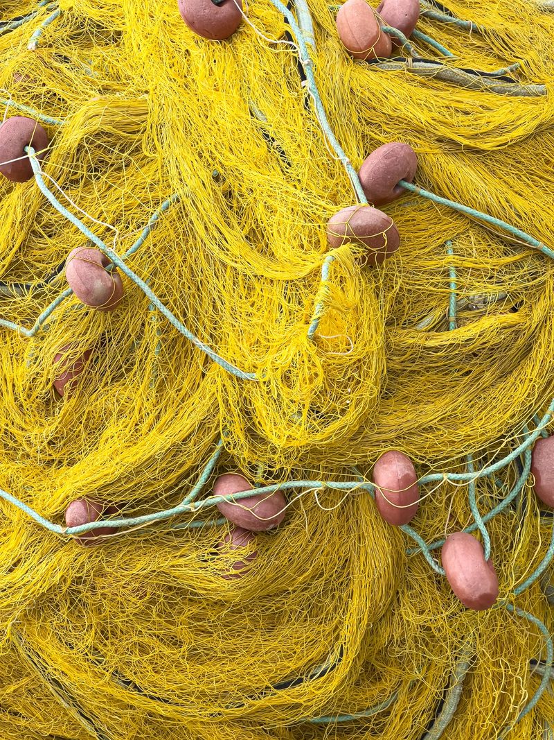 Close up of a tangled bright yellow fishing net with red floats and blue ropes