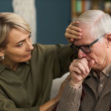 A woman comforts an elderly man who is upset.