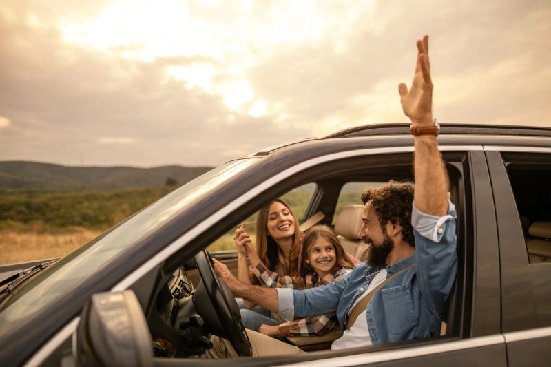 Happy family driving car on vacation at sunset, feeling freedom and joy