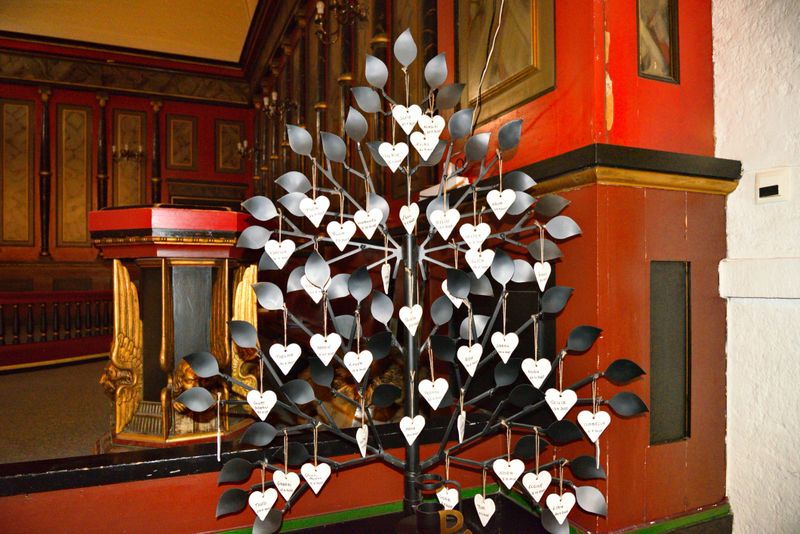 A heart tree stands inside the old Narvik church in Norway. White hearts hang from branches, showing messages and wishes left by visitors in a meaningful space for all.