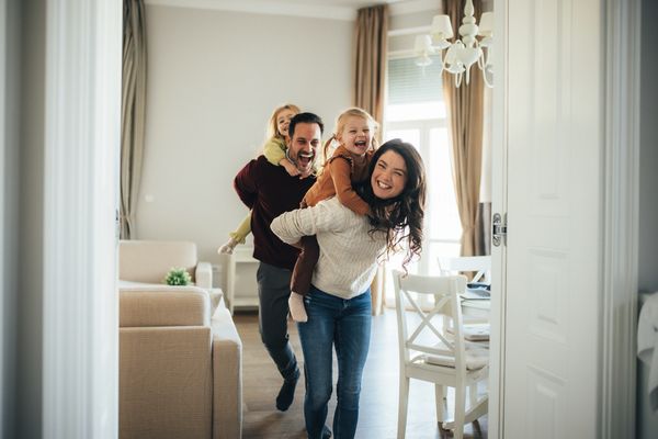 A joyful family playing piggyback inside their home.
