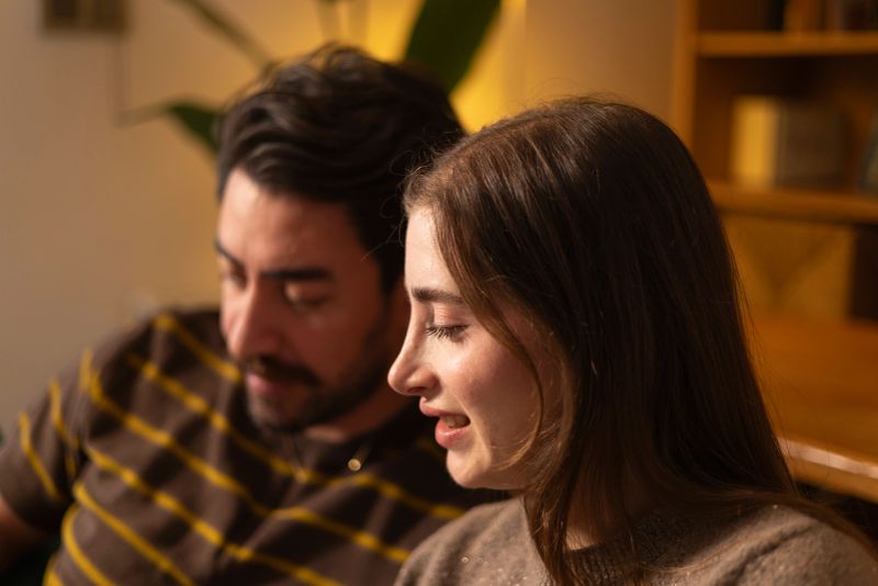 Young man and woman spending quality time together sitting on a couch, relaxing in the warmth and comfort of their home, finding joy in shared moments