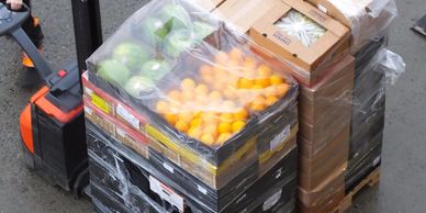 Pallet loaded with fruits and boxes wrapped in plastic on a forklift.