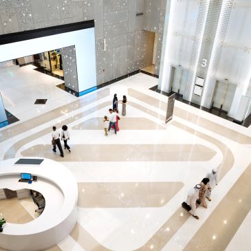 People walking inside a modern, spacious building lobby.