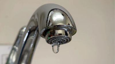 Close-up of a water drop hanging from a faucet.