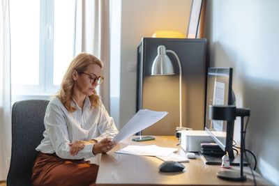 Business owner reviewing unpaid invoices at her desk