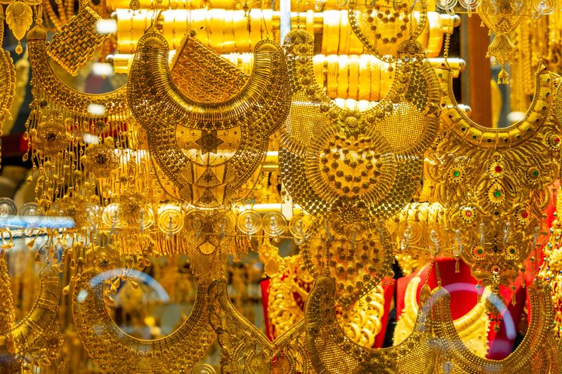 A display of various types of gold jewelry including gold chains, collars, watches and various others.