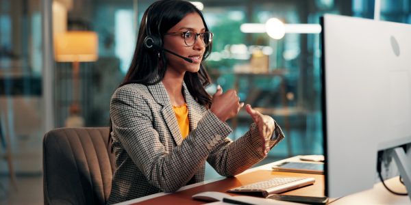 Customer service representative talking with headset in modern office.