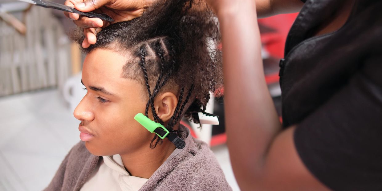 Man getting his hair braided with clips in place.