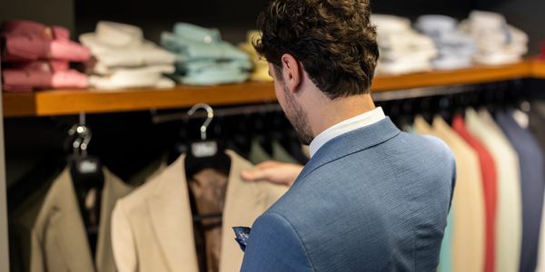 Man browsing beige jackets in a clothing store.