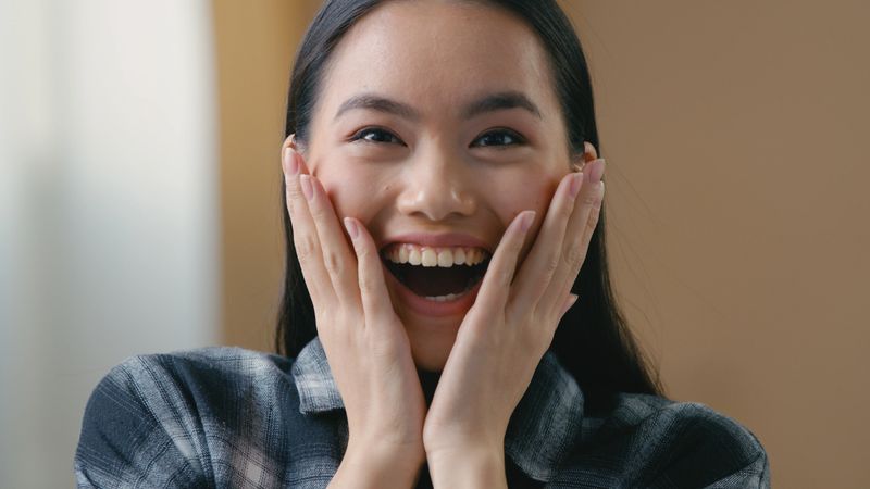 Surprised amazed excited Asian woman wow expression looking at camera shocked happy female victory good news success Korean girl celebrating win triumph winning bid getting offer joyful face at home. High quality 4k footage