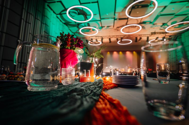 Dining table is elegantly arranged with glassware, floral decorations, and soft lighting, creating a warm and inviting ambiance for a celebration or gathering