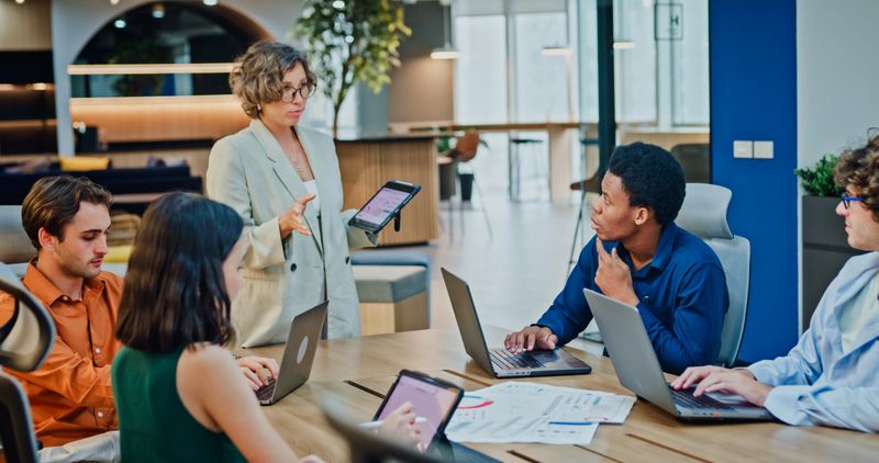 Diverse business team presents company data and performance charts meeting discussing strategy planning investment marketing strategies in office. Sustainable business and finance concept.