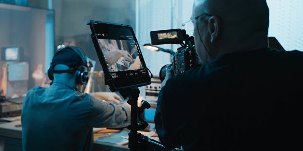 Filming a person working at a desk with video equipment.