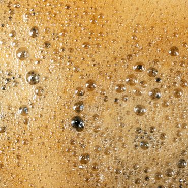 Close-up of coffee foam with bubbles on the surface.