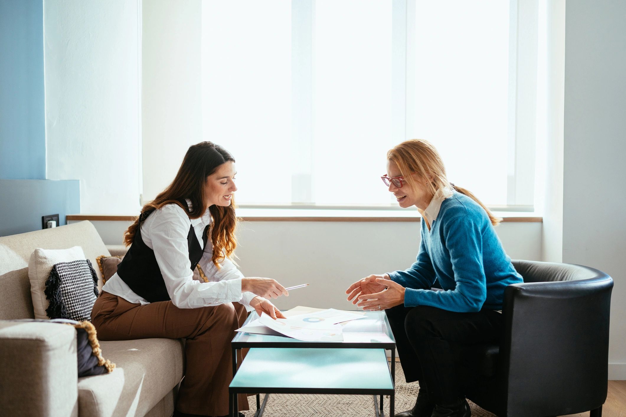 Two women discussing documents in a cozy room.