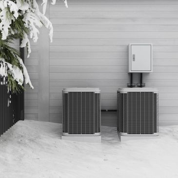 Two air conditioning units outside a house covered in snow during winter.