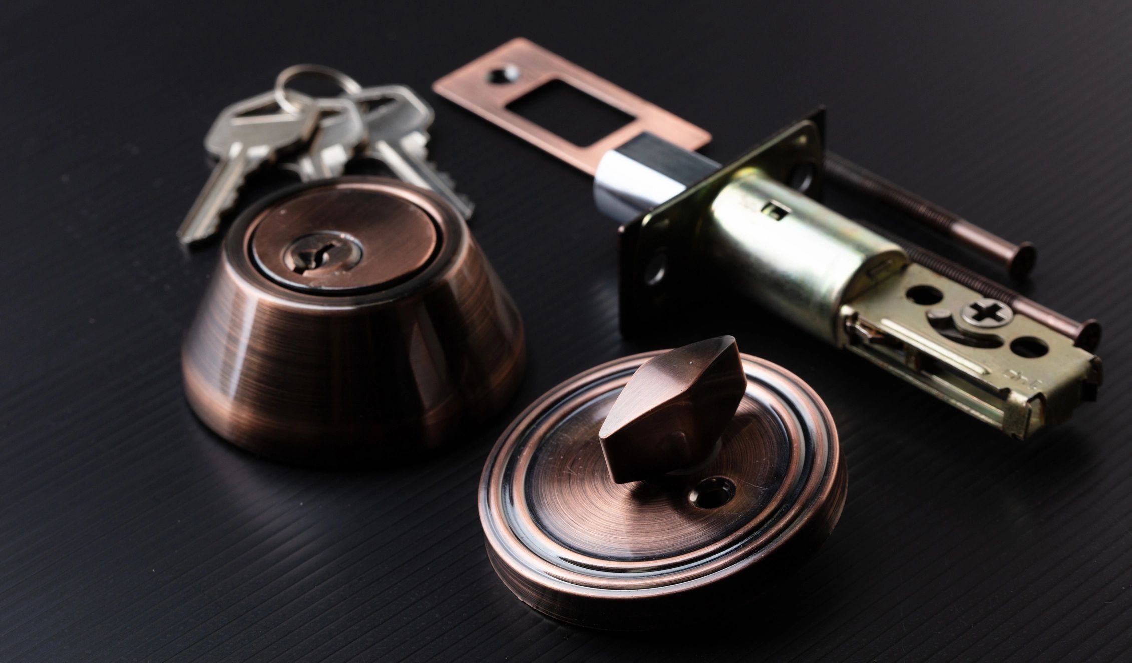Door lock parts with keys on a black surface.