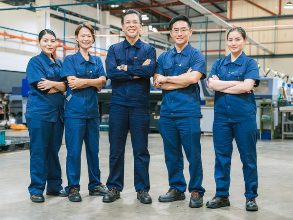 Equipe industrial em uniformes azuis posando confiante.