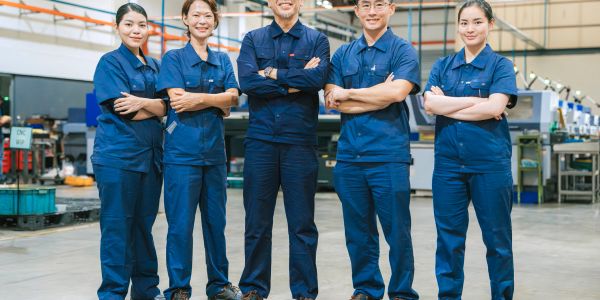 Equipe industrial em uniformes azuis posando confiante.