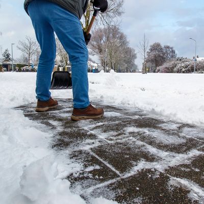 Person shoveling snow off a sidewalk.