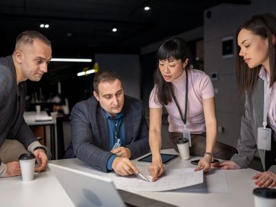 Four professionals discussing plans over documents in an office.