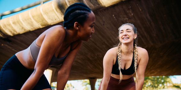 Two women smiling during an outdoor workout.
