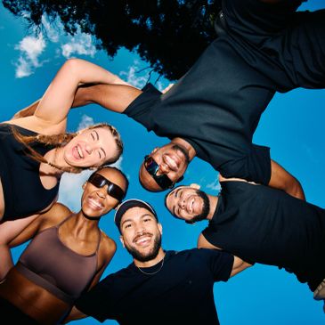 Group of friends smiling in a circle outdoors.