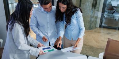 Tres personas revisan documentos en una oficina.