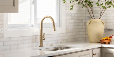 Modern kitchen sink with gold faucet and white countertop.