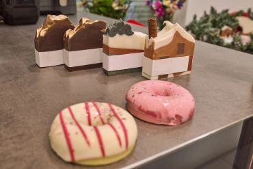 Two glazed donuts and four soap bars shaped like cake slices on a table.