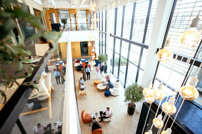 High angle view on group of business people in lobby of modern office building with large windows, collaborating with each other