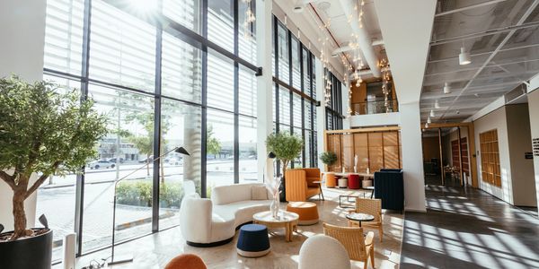 Bright, modern lounge with large windows and stylish furniture.