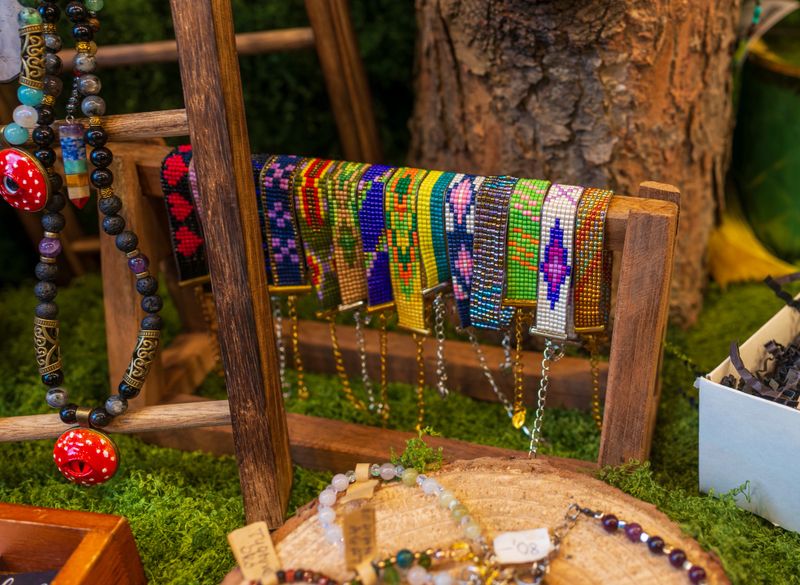 Bright handmade beaded bracelets are arranged on a rustic wooden stand. Rich colors, detailed patterns, and natural textures highlight craftsmanship, creativity, and artisanal jewelry design.