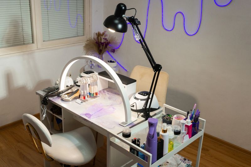 Modern manicure workspace in beauty salon with professional table, lamps, tools and cosmetics. Nail technician workstation setup, nail care service and beauty industry interior concept