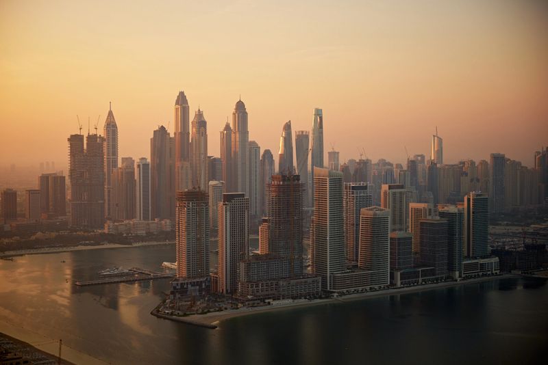 Dubai Marina cityscape at golden hour with numerous towering buildings and water.