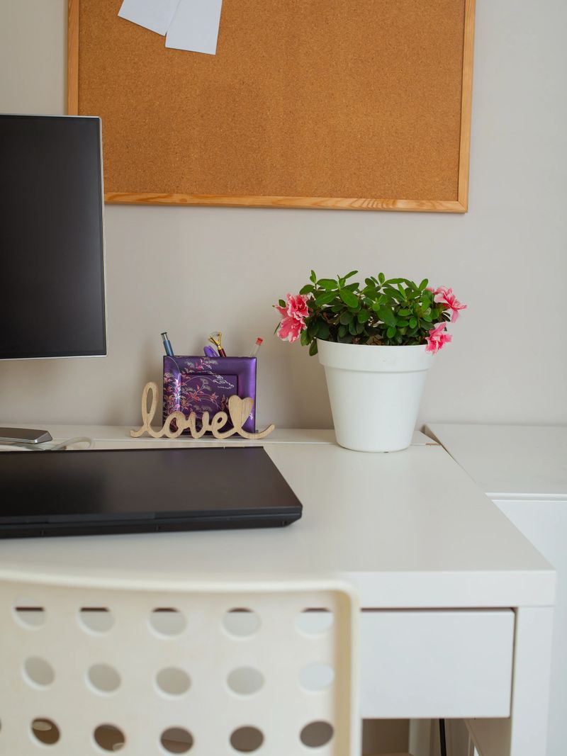 Bright, cozy home office setup with laptop, floral plant, and wooden 'love' sign on a white desk. Perfect for remote work, productivity, or interior lifestyle content.