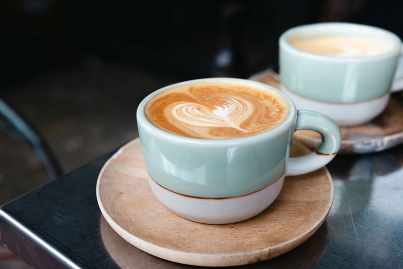 Latte with heart shape froth art serving on coffee shop table.