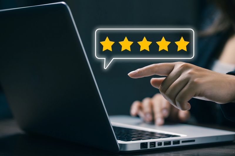 Hand pointing to five star rating on laptop screen, representing online reviews, customer feedback, digital reputation, service evaluation, and trust building in modern business platforms.