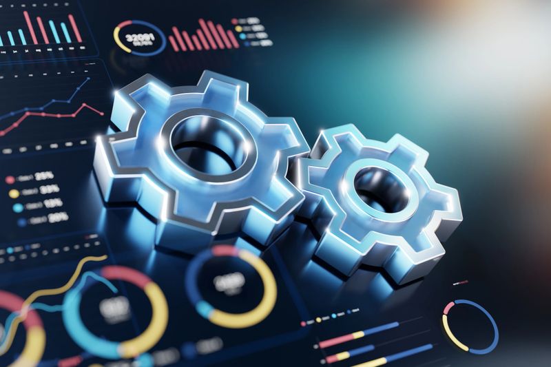 A close-up scene of shiny blue gears beside futuristic charts and graphs, illustrating technology, automation, and optimization. The image conveys engineering accuracy, data-driven decision making, and efficient workflow in modern industries.