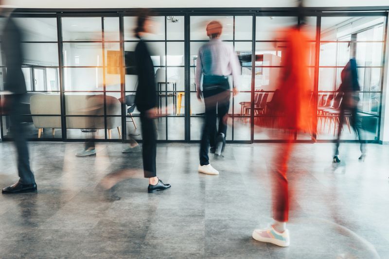 Blurred motion of energetic businesspeople on the go and project team members discussing ideas in a conference room