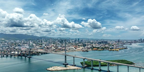 A cable-stayed bridge over a body of water with a city skyline in the background.