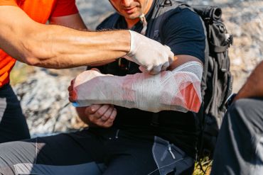 Person receiving arm first aid outdoors.