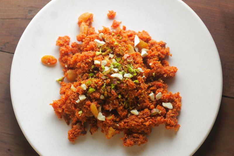 Traditional Indian carrot halwa served on a white plate and garnished with chopped nuts, ready to be enjoyed as a sweet dessert.