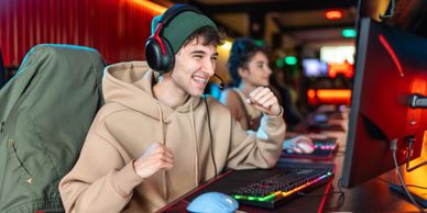 Young man enjoying gaming session with headset on in a vibrant gaming setup.
