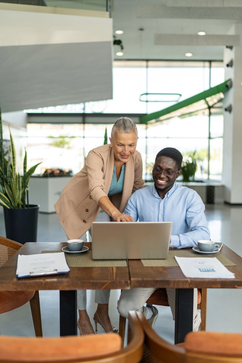 Multiracial colleagues engaging in a discussion, working together on a laptop, and sharing ideas during a casual meeting in a bright contemporary workplace