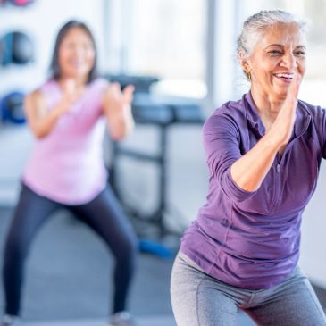 Two women exercising indoors, smiling and focused.