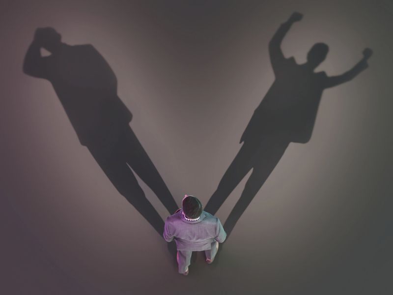 A person stands in a dimly lit space. Their shadows stretch behind them, creating different shapes on the ground. The event takes place at night, highlighting the surroundings. Choice and possibilities concept.